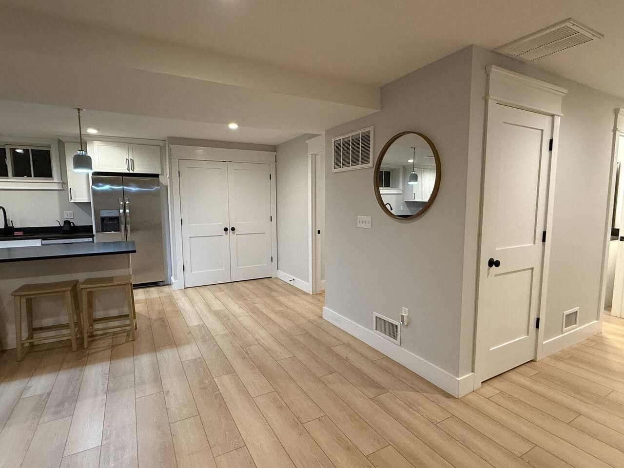 Una cocina moderna con armarios blancos, un refrigerador de acero inoxidable y una isla de madera con taburetes.
