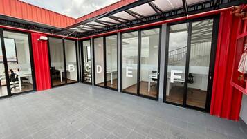 A modern office space with glass partitions, red accents, and a grey floor.