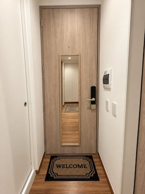 A hallway with a wooden door, a welcome mat, and a light switch on the wall. - Sophisticated Apartment in Chapinero Norte Bogota (Bogotá)
