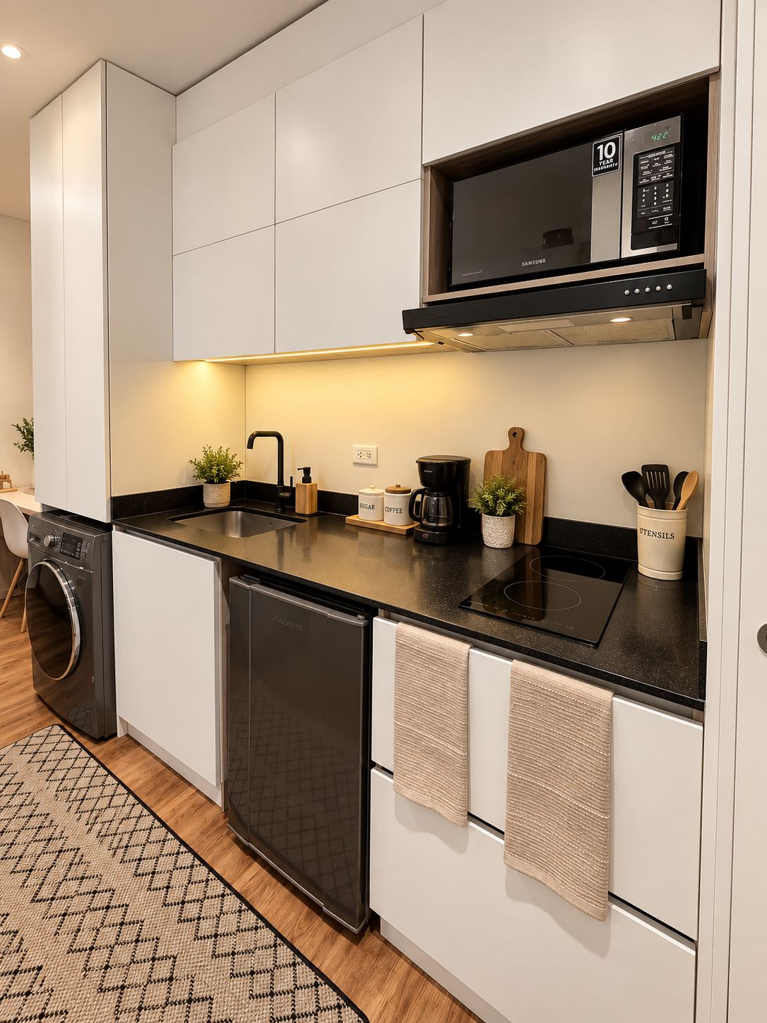Una cocina moderna con armarios blancos, encimera negra, microondas integrado y lavavajillas.