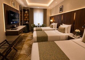 Habitación de hotel con dos camas, un escritorio, un televisor y una zona de estar.
