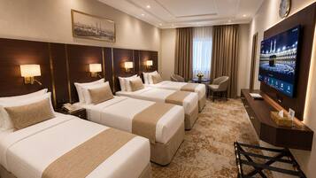 A hotel room with three beds, a TV, a desk, and a clock on the wall.