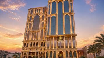 A hotel with a prominent tower, arched windows, and a sign indicating it is the Al Moudania Hotel.