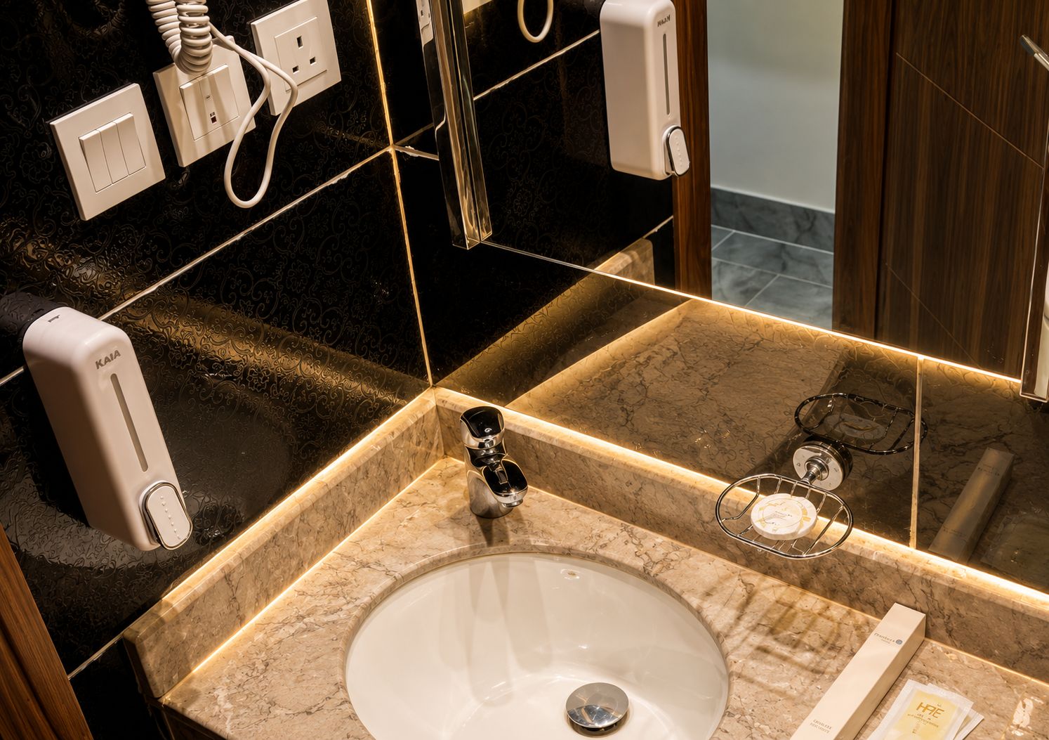 A bathroom with a marble sink, a mirror, a towel rack, and a hand dryer.