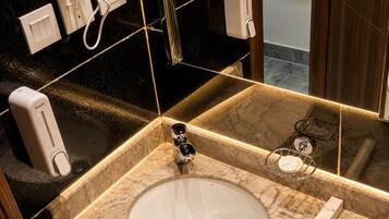 A bathroom with a marble sink, a mirror, a towel rack, and a hand dryer.