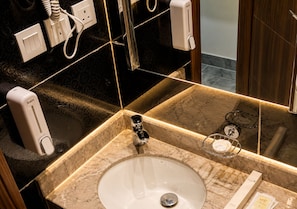 A bathroom with a marble sink, a mirror, a towel rack, and a hand dryer. - HINDIBAA HOTEL MAKKAH (Makkah)