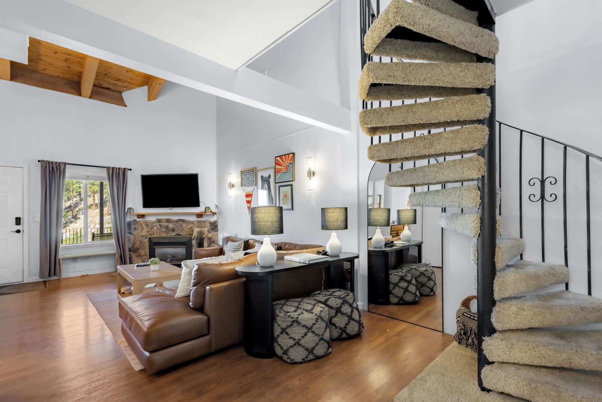 A spacious living room with a fireplace, a sofa, a coffee table, and a staircase with a unique design.