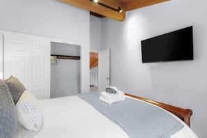 A bedroom with a bed, a TV mounted on the wall, and a door leading to a bathroom. - Après Tahoe - 4BR Mountain Home (Stateline)