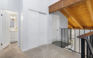 A hallway with white doors, a wooden ceiling, and a staircase with a metal railing. - Après Tahoe - 4BR Mountain Home (Stateline)