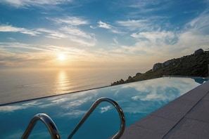 Une piscine à débordement offrant une vue imprenable sur l’océan et le coucher de soleil.