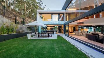 A modern house with a well-maintained lawn, outdoor seating, and a swimming pool.