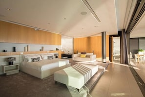 Une chambre d’hôtel moderne, dotée d’un grand lit, d’un canapé, d’une table basse et offrant une vue sur l’extérieur.