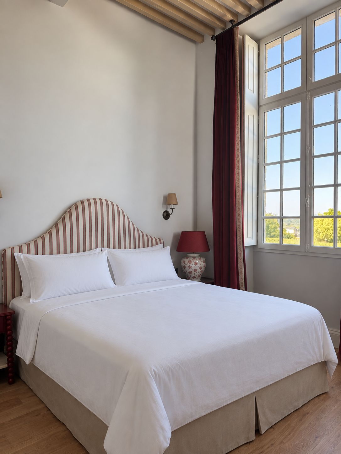 A bed with white bedding, a striped headboard, and a nightstand with a lamp.