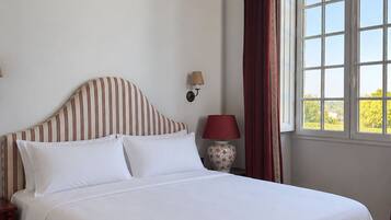 A bed with white bedding, a striped headboard, and a nightstand with a lamp.