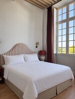 Una cama con ropa de cama blanca, un cabecero a rayas y una mesita de noche con una lámpara.