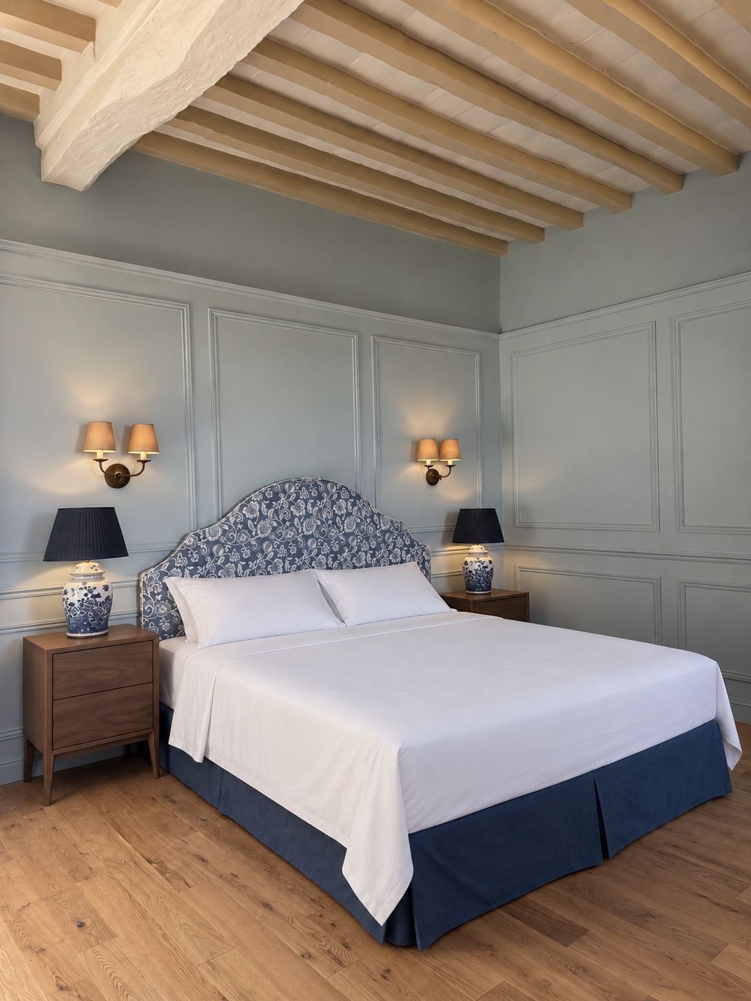 Een slaapkamer met een bed, nachtkastjes, wandlampen en een houten plafond.