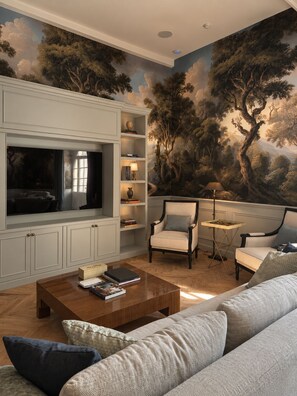 A living room with a large flat-screen TV, a sofa, two armchairs, a coffee table, and a bookshelf. - Chateau Gamage (Saint-Pey-de-Castets)