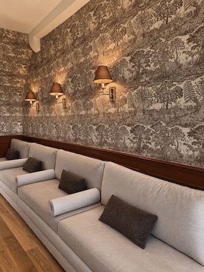 Una habitación con un conjunto de sofá, un papel tapiz estampado y lámparas de pared.