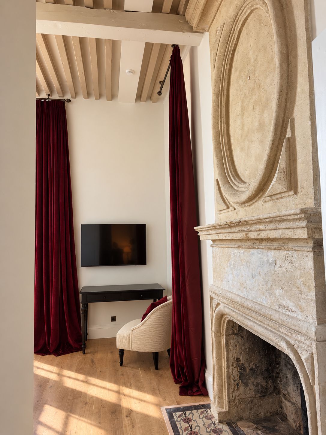 A room with a fireplace, a television mounted on the wall, and a desk with a chair.