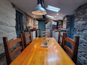 Eine rustikale Küche mit Steinsäulen, einem Holztisch und einer blauen Tür.