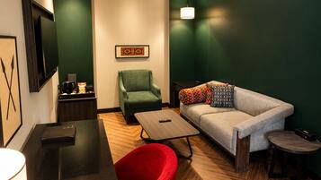 A modern hotel room with a sofa, armchair, and a small table.