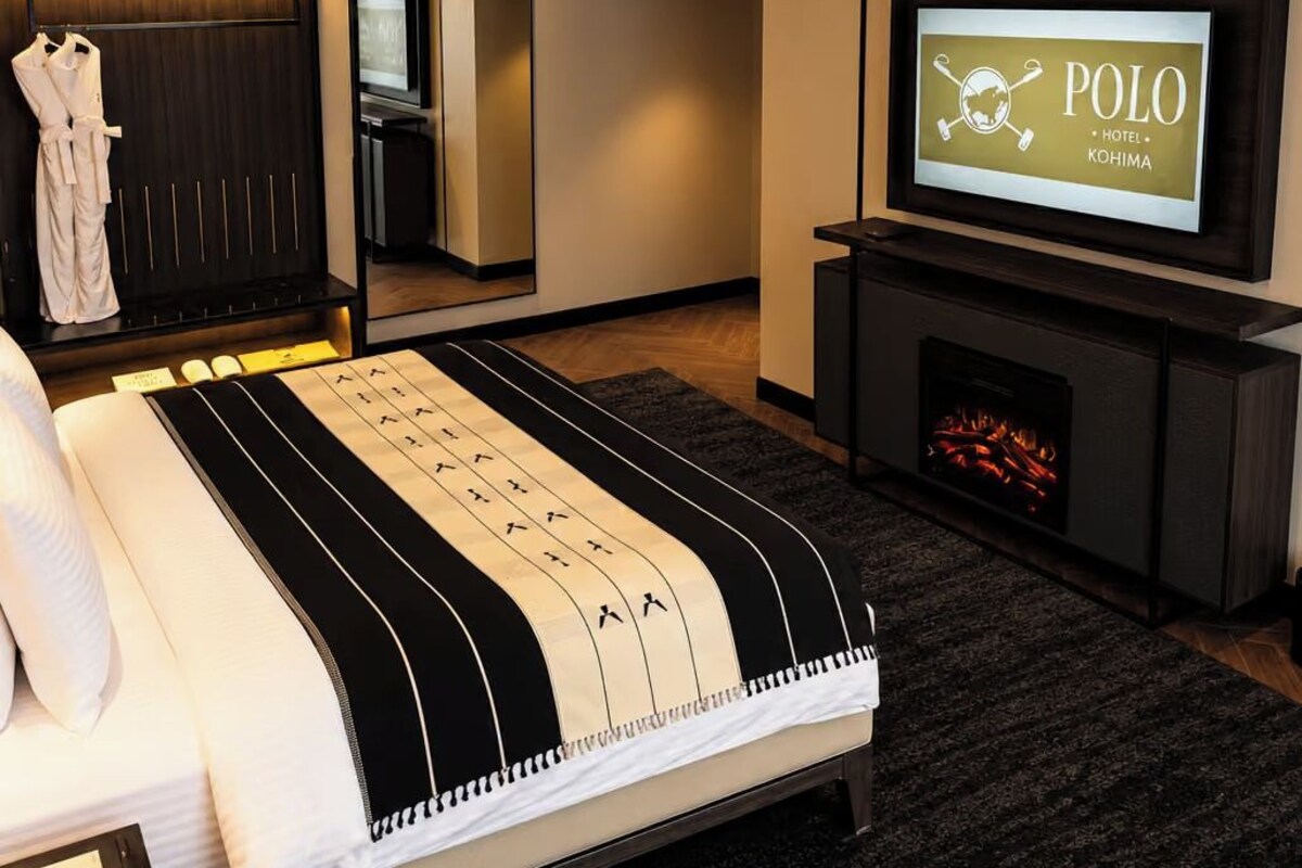 A hotel room with a bed, a television, a fireplace, and a wardrobe.