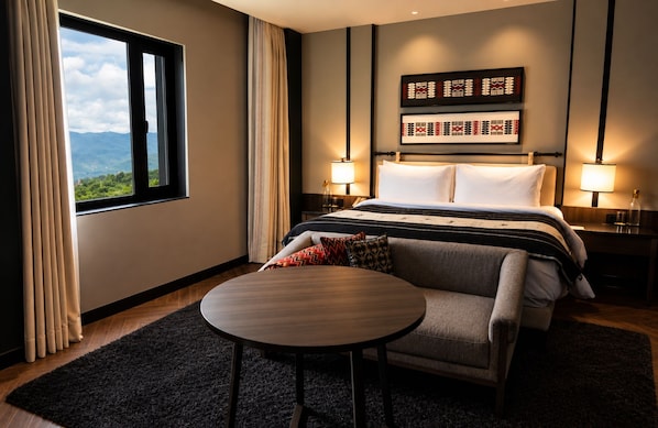 A hotel room with a bed, a round table, a sofa, and a view of the outdoors. - Polo Hotel, Kohima (Kohima)