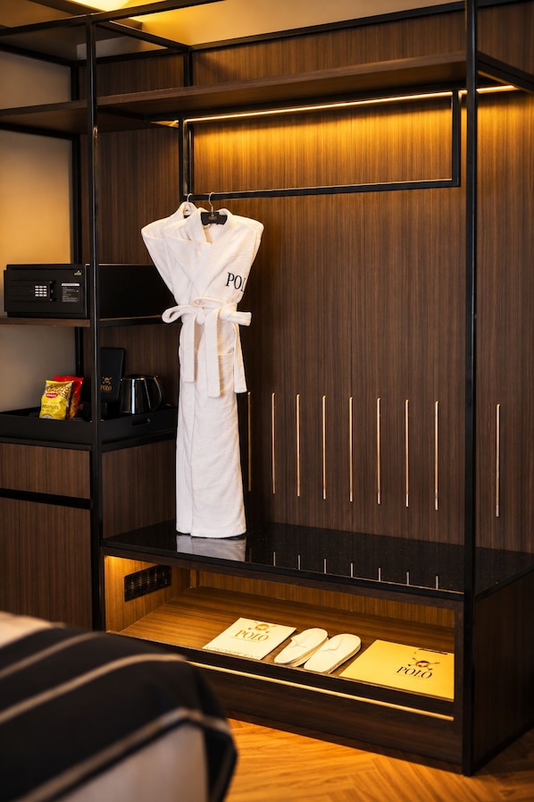 A hotel room with a wardrobe containing a white robe, a coffee machine, and a minibar.