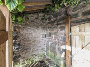 Une pièce aux murs de pierre, dotée d’une porte en bois et d’une petite fenêtre.