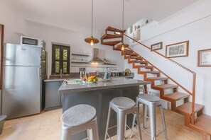 A modern kitchen with a central island, stainless steel appliances, and a wooden staircase. - Gorgeous 2-bedroom building with AC in charming Antalya (Antalya)