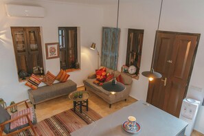 A cozy living room with a sofa, a coffee table, and a dining table. There are decorative pillows, a lamp, and a clock on the wall. - Gorgeous 2-bedroom building with AC in charming Antalya (Antalya)