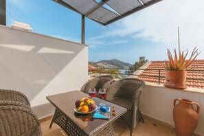 A balcony with wicker chairs, a table with fruit and drinks, and a view of a coastal landscape. - Gorgeous 2-bedroom building with AC in charming Antalya (Antalya)