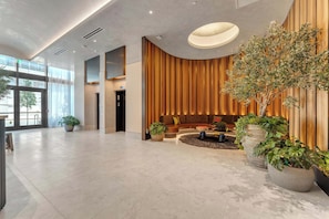 A spacious lobby with a modern design, featuring a seating area with a sofa and a coffee table, and several potted plants. - E11even Miami Elevated Luxury Living (Miami)
