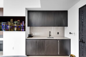 A modern kitchen with dark wood cabinets, a stainless steel sink, and a cityscape view. - E11even Miami Elevated Luxury Living (Miami)