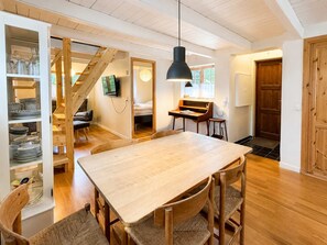 A spacious room with a wooden dining table, chairs, a staircase, and a television.