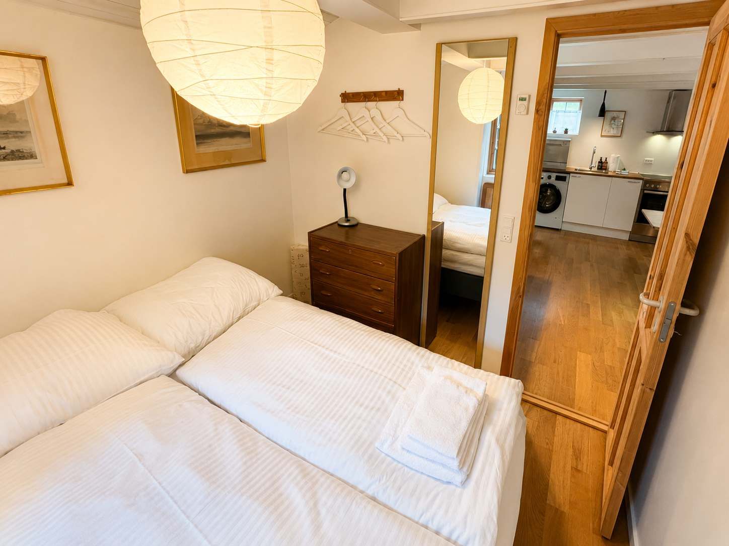 Une chambre à coucher avec un lit, une table de chevet, un miroir et une vue sur la cuisine.