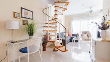 Una sala de estar moderna con una escalera en espiral, un conjunto de sofá, un comedor y una planta en maceta.
