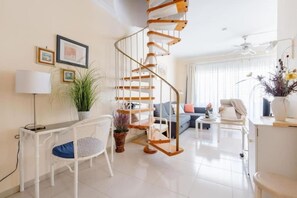 A modern living room with a spiral staircase, a sofa set, a dining area, and a potted plant. - Golf Park Sunny Cozy Penthouse Near the Ocean (San Miguel de Abona)