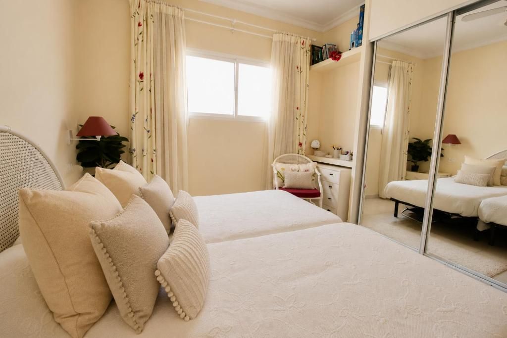 Un dormitorio con cama, escritorio, silla y espejo.