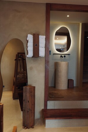 A bathroom with a wooden vanity, a towel rack, and a mirror with a wooden frame. - Hide and Sea Koh Tao (Koh Tao)