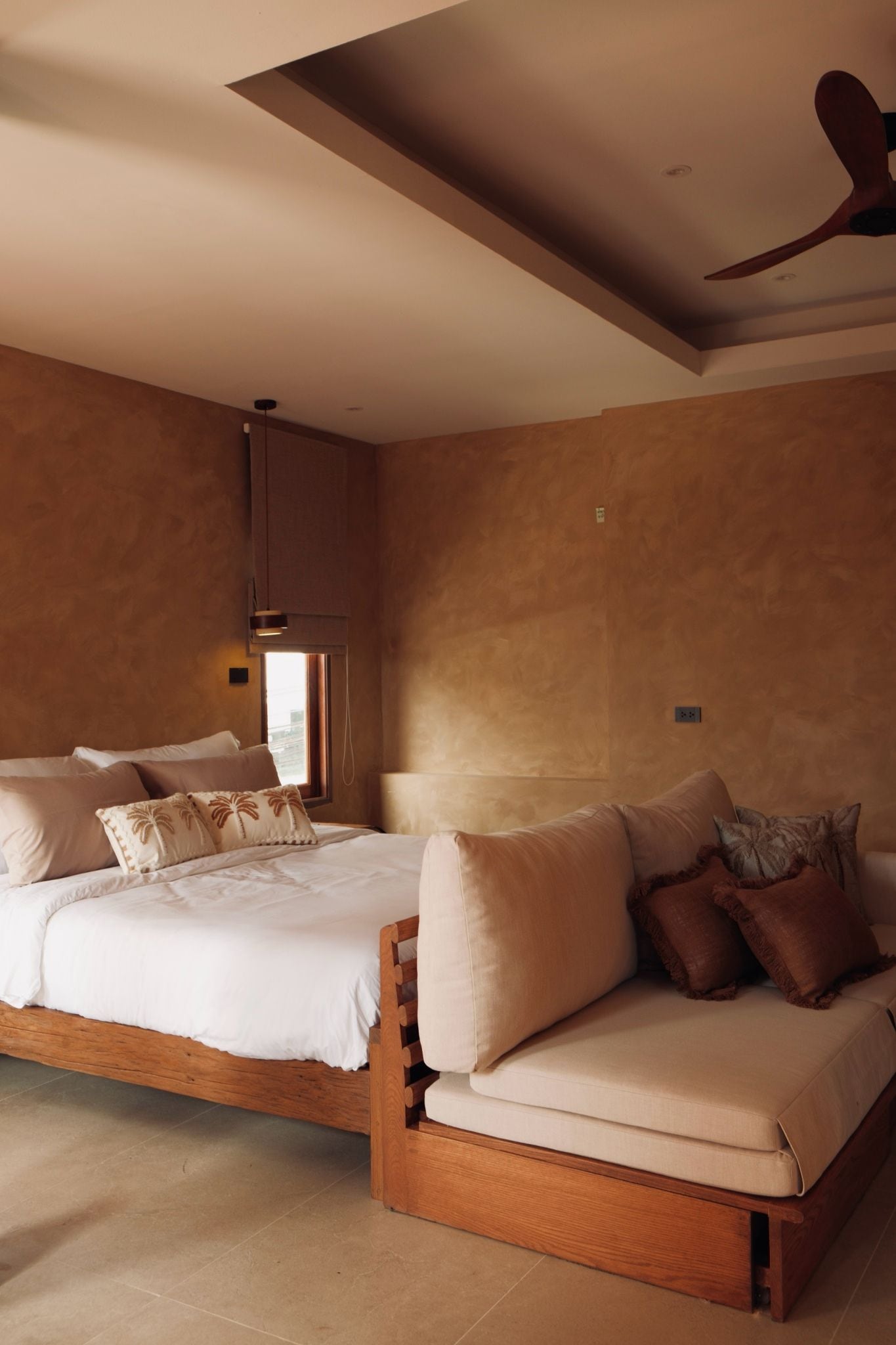 A bedroom with a large bed, a sofa, and a ceiling fan.