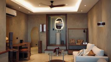 A modern living room with a glass coffee table, a sofa, a wooden side table, and a ceiling fan.