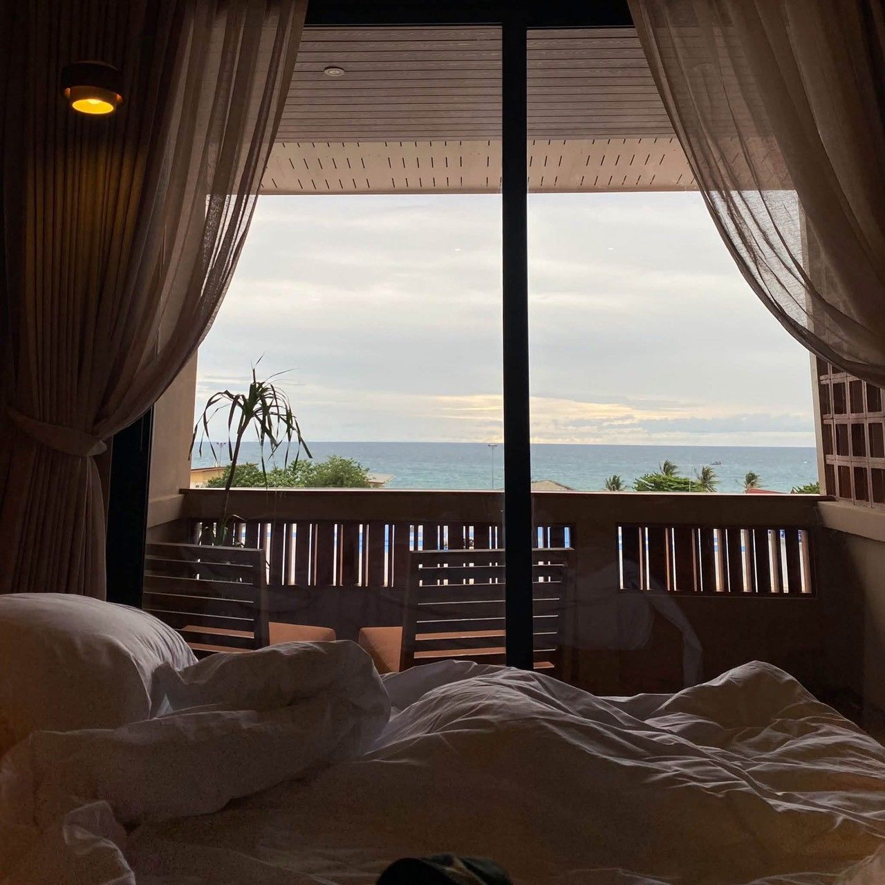 Un dormitorio con un ventanal grande que da a un balcón y vistas al mar.
