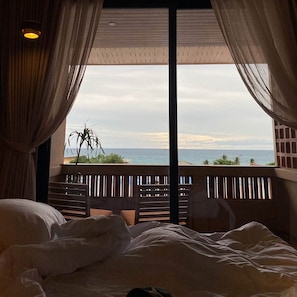 Un dormitorio con un ventanal grande que da a un balcón y vistas al mar.
