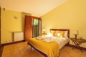 A hotel room with a bed, a nightstand, a lamp, and a view of the outdoors. - Farmhouse - Beach, Pool and Jacuzzi with Sea View (Viana do Castelo)