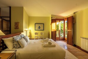 Ein Hotelzimmer mit einem Bett, zwei Stühlen, einem Gemälde und Blick ins Freie.