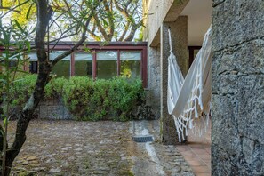 A stone pathway leading to a building with a window and a hammock. - Farmhouse - Beach, Pool and Jacuzzi with Sea View (Viana do Castelo)