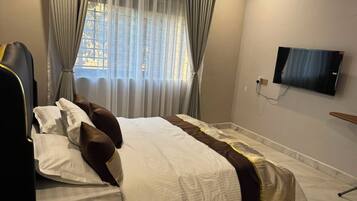 Une chambre d’hôtel avec un lit, des rideaux, une télévision et une fenêtre donnant sur un paysage agréable.