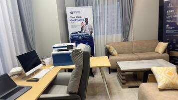 Une chambre d’hôtel équipée d’un bureau, d’un ordinateur portable, d’une imprimante et d’un canapé avec des coussins.