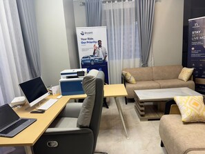 Une chambre d’hôtel équipée d’un bureau, d’un ordinateur portable, d’une imprimante et d’un canapé avec des coussins.